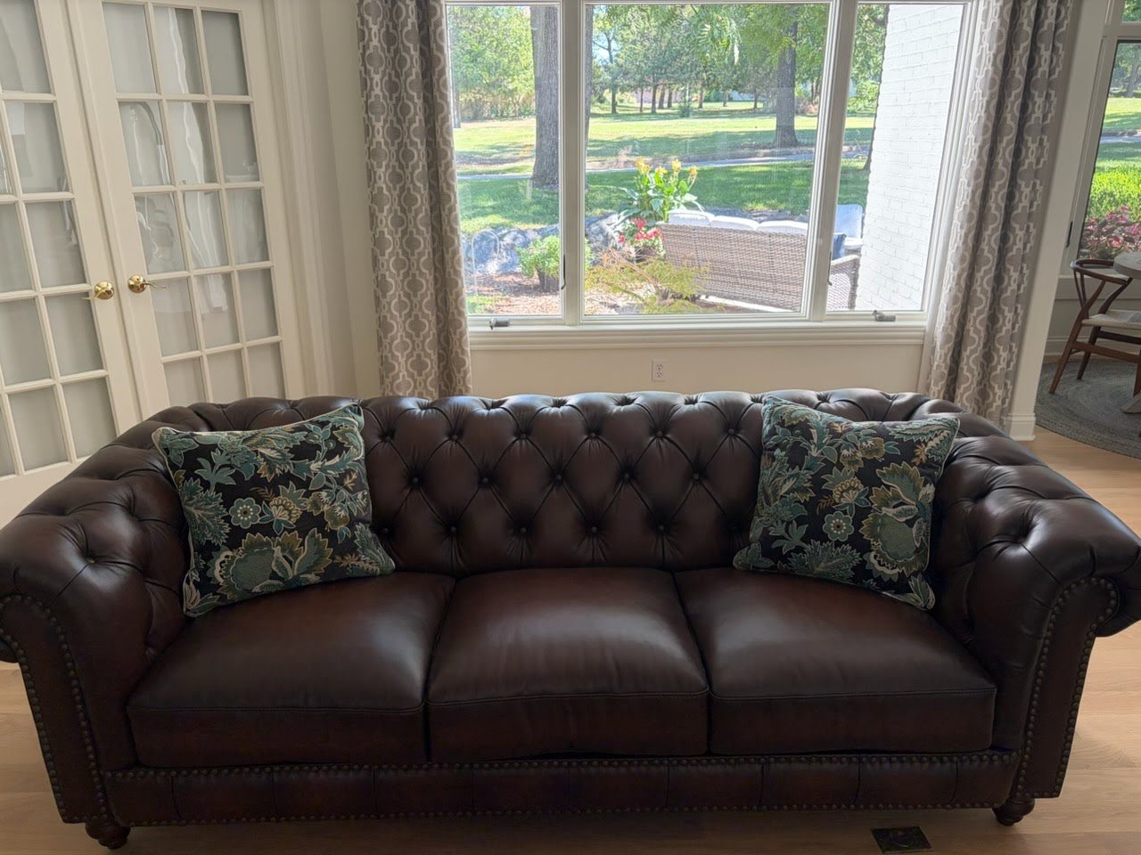 Tufted leather Chesterfield sofa by a window